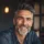 Homme souriant aux cheveux gris et barbe grise.